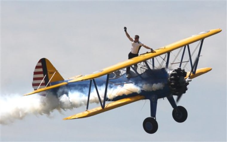 Wing walker Todd Green, riding John Mohr's Steerman aircraft, waves to the crowd Sunday at the beginning of their demonstration during an air show at Selfridge Air National Guard Base in Harrison Township, Mich.